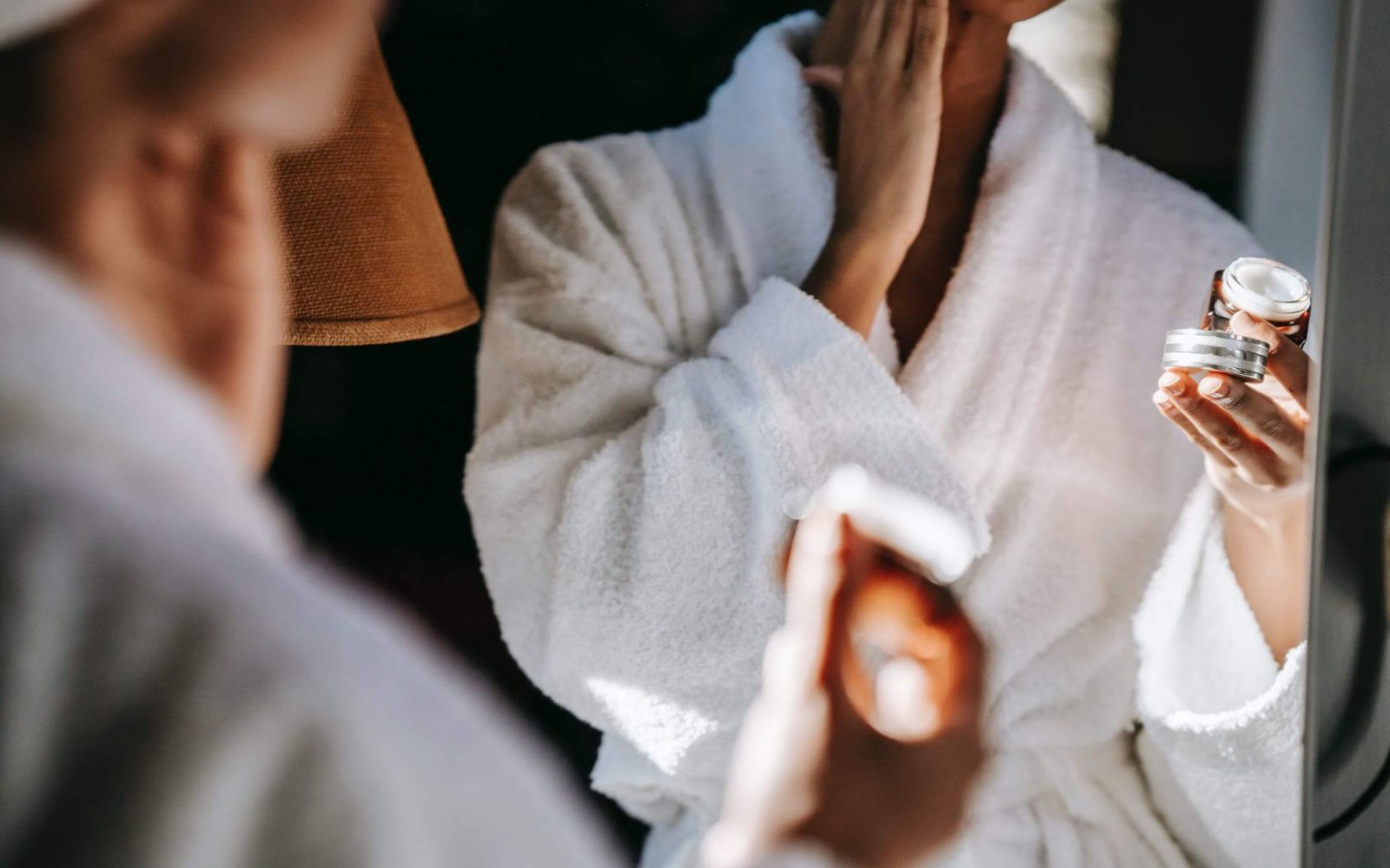 a woman in a robe applying cream to her face